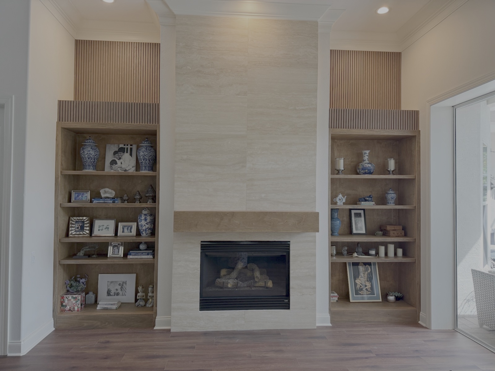 Custom wood built-in bookcases flanking stone fireplace with vertical slat accents in Sarasota FL