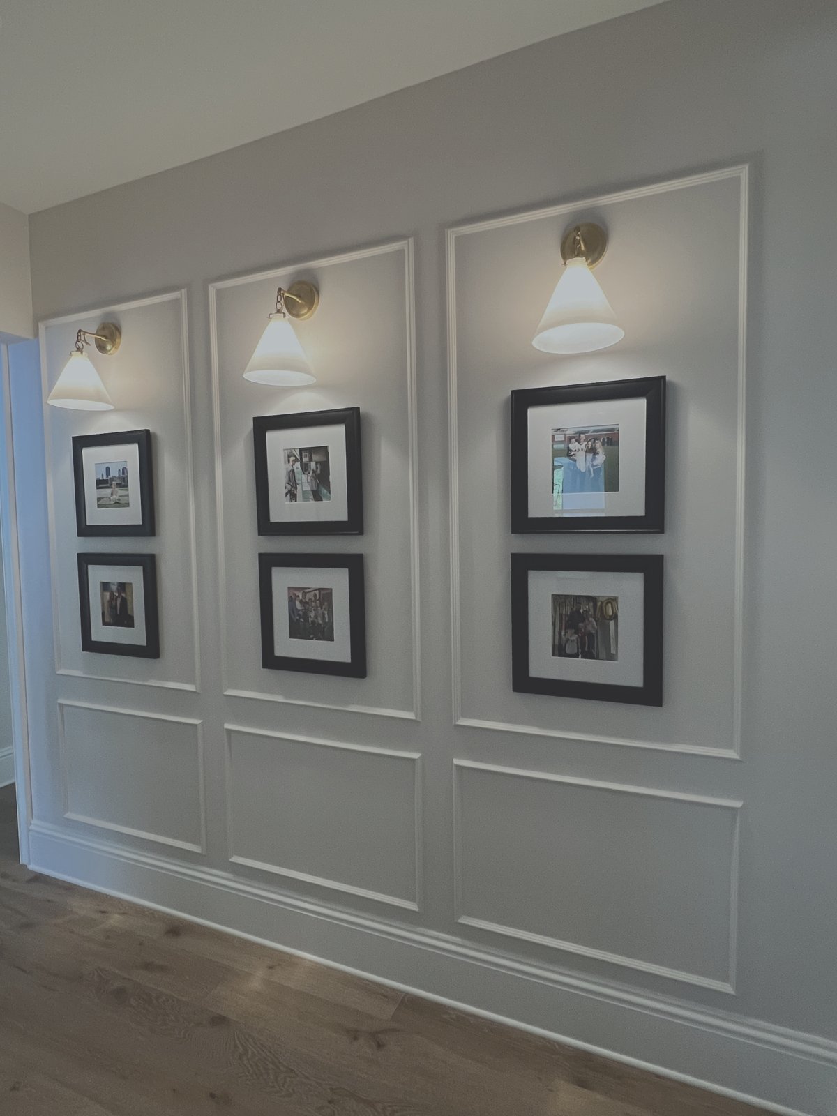 Full wall grid trim moulding with illuminated picture gallery frames and classic wall sconces