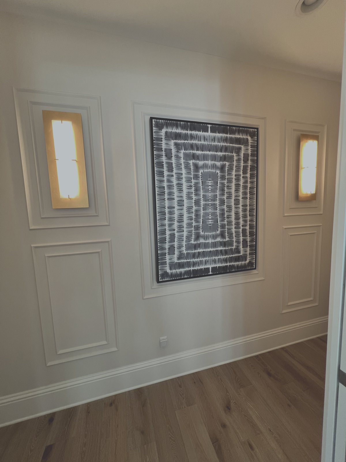 Custom picture frame moulding wall trim with integrated gold art lighting fixtures in luxury Florida home