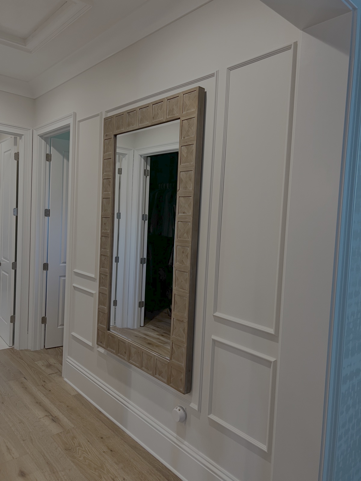 Classic picture frame wainscoting wall moulding, tall baseboards, and cased door openings in Florida hallway