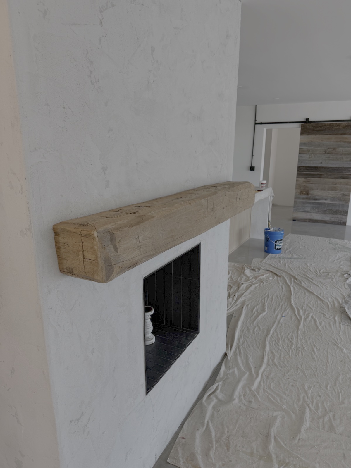Handcrafted solid timber hand-hewn rustic fireplace mantel mounted on white plaster in Southwest Florida